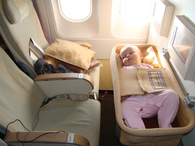 Маленький инфант крепко спит в самолете. Такие малыши всегда летают с родителями