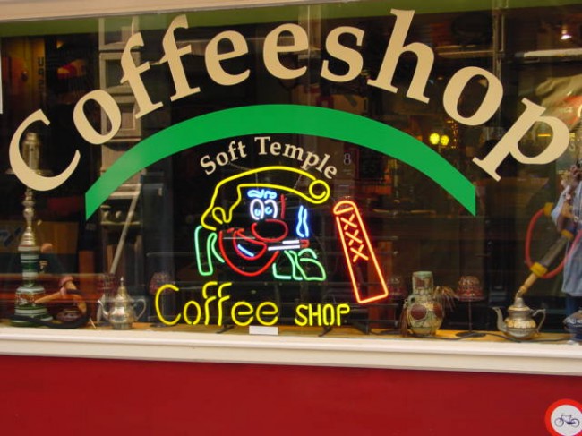 Coffee shop Амстердама выделяется из окружающих магазинчиков своей яркой вывеской