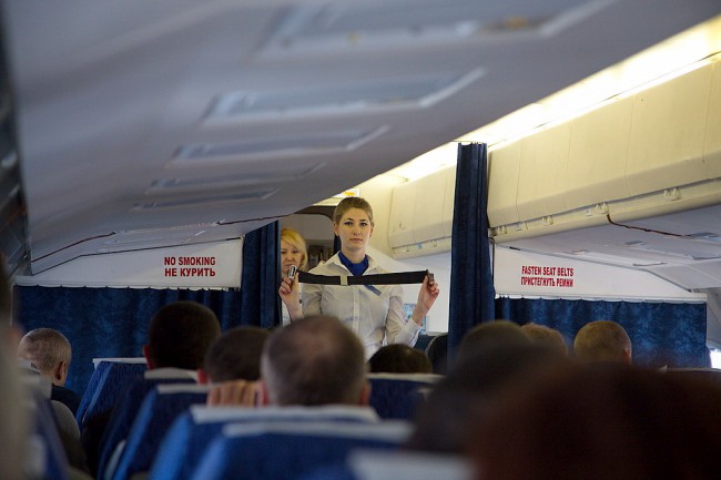 Стюардесса демонстрирует пассажирам, как нужно застегивать ремни безопасности.