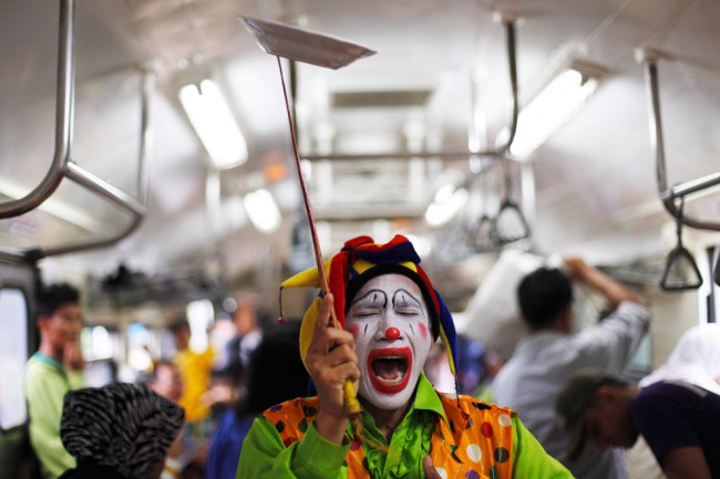 Клоун Andri Hendri выступает в пригородных поездах в Джакарте